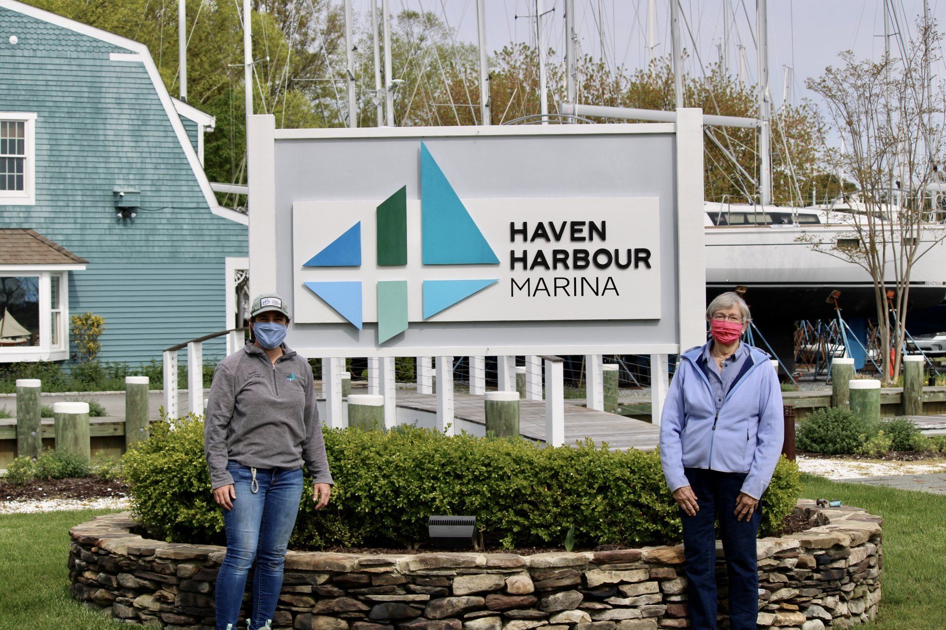 Employee and customer pose outside in front of business sign