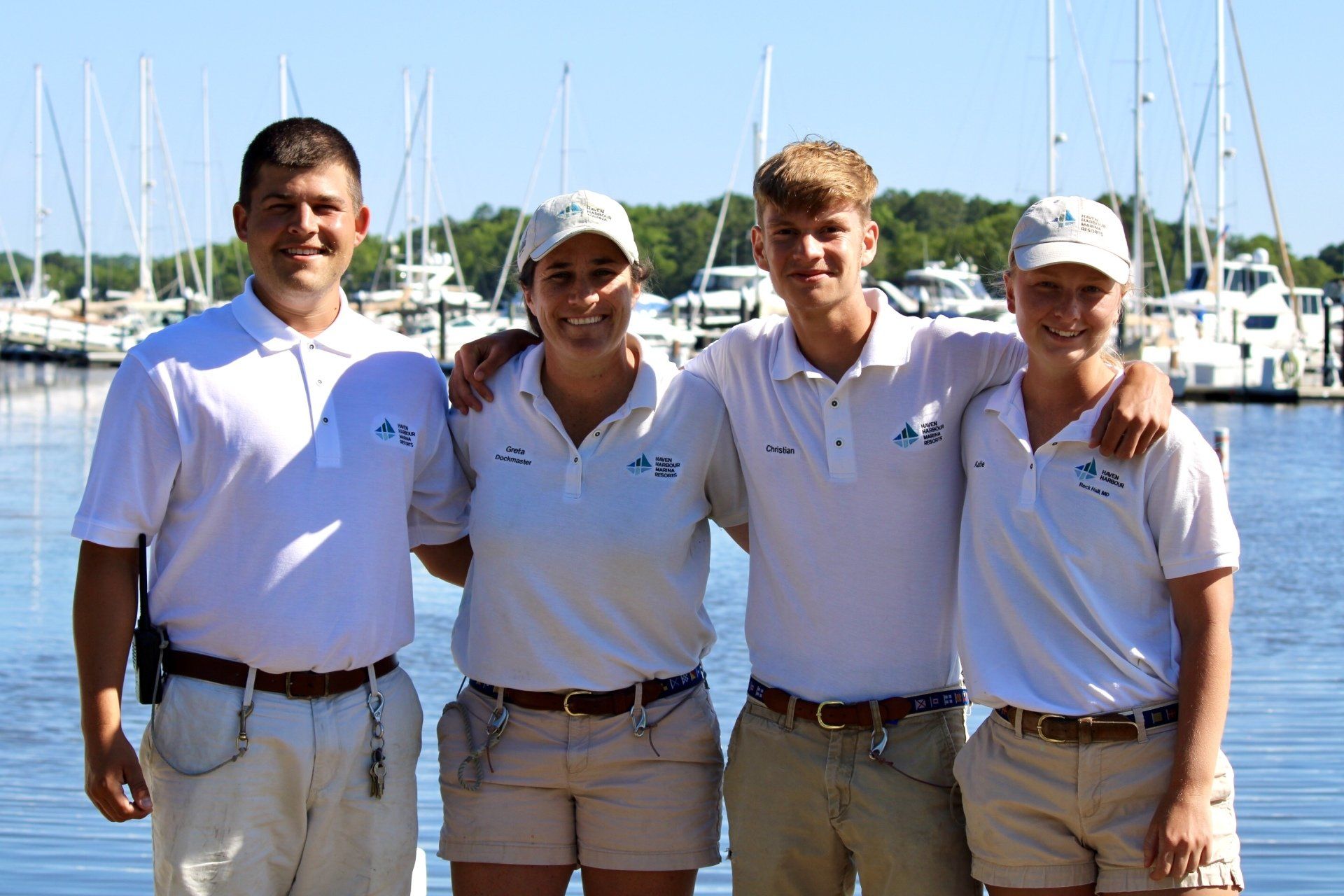 Group of employees pictured outside on a sunny summer day with boats in the background