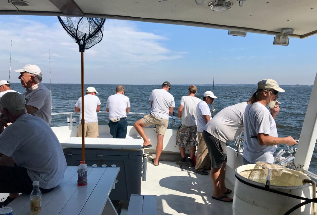 People fishing and talking aboard a boat