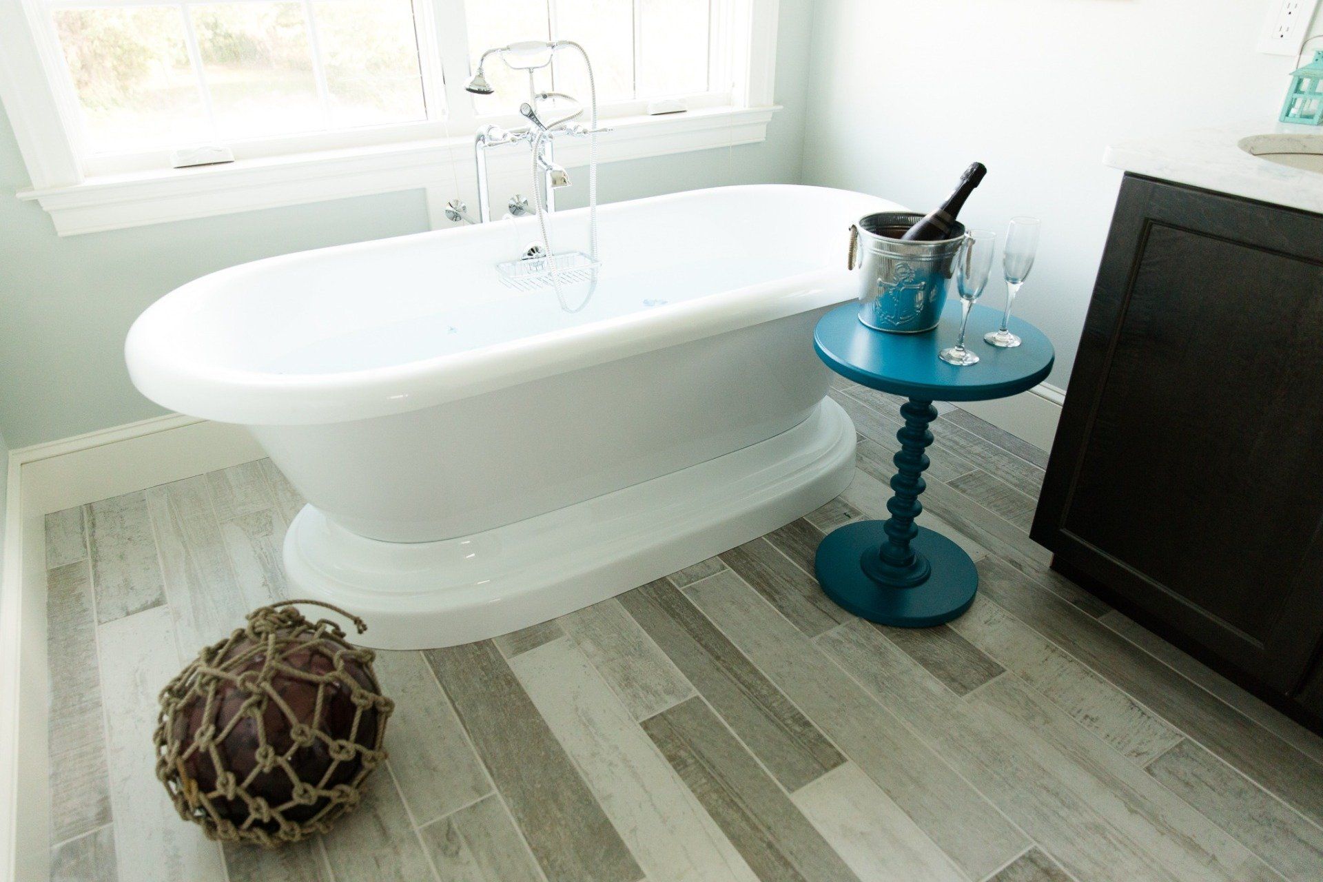 White soaking bath tub with tiled floor and blue side table