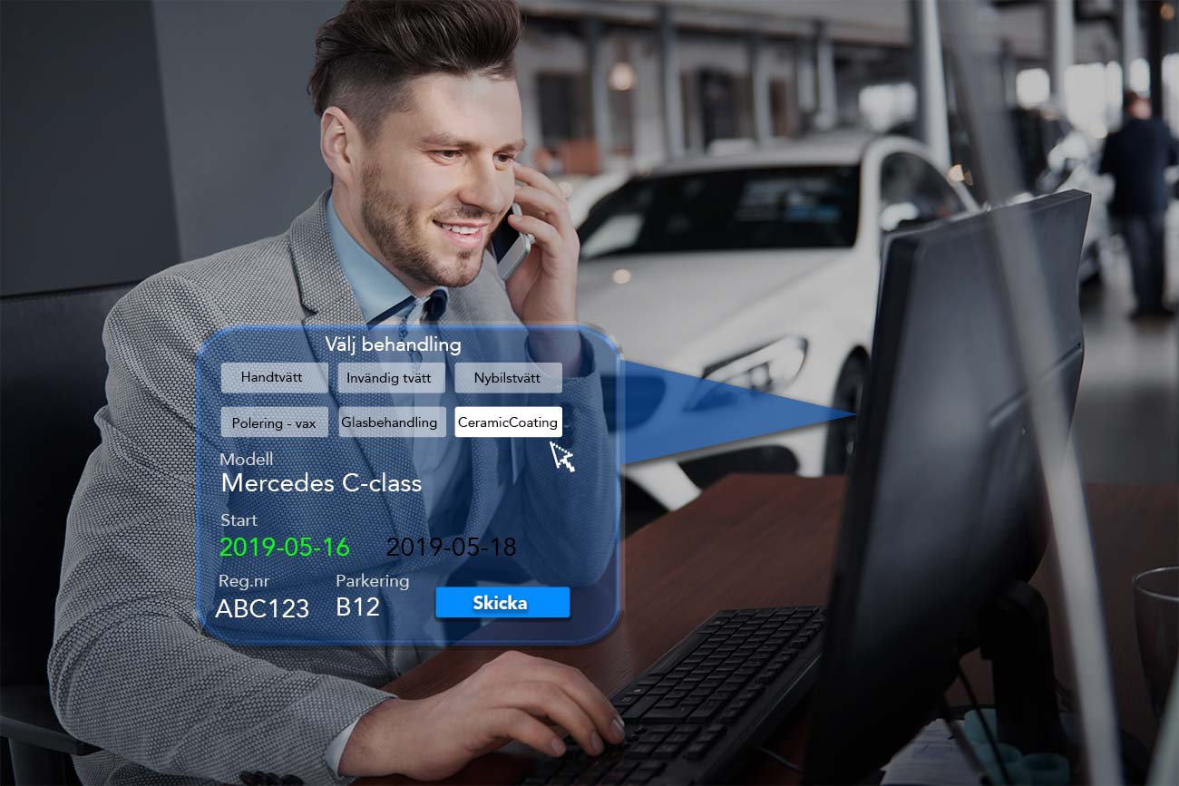 A man is sitting in front of a computer talking on a cell phone.
