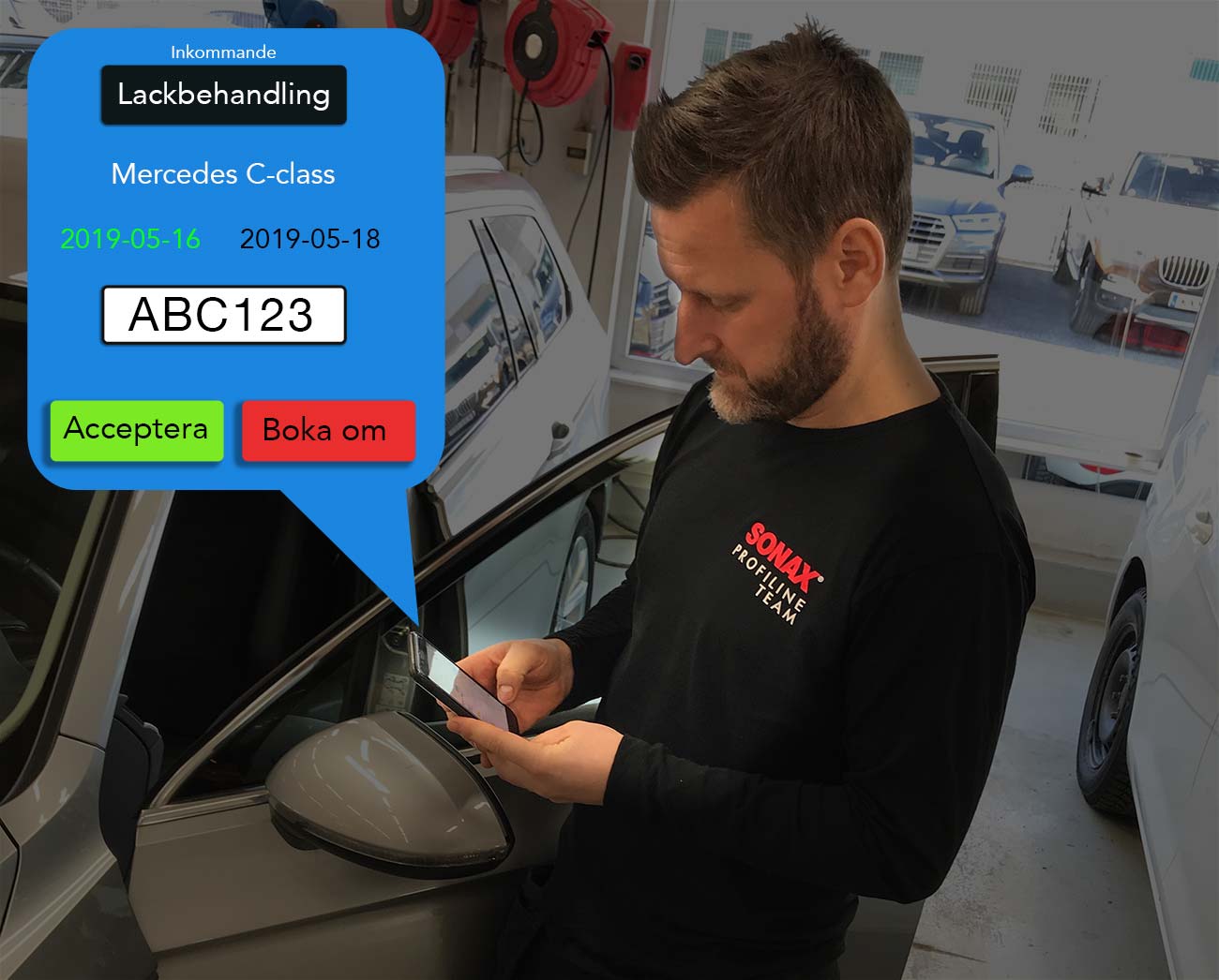 A man is looking at his phone while standing next to a car