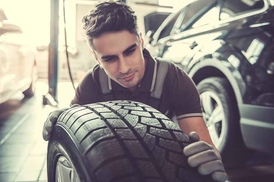 A man is looking at a tire in a garage.