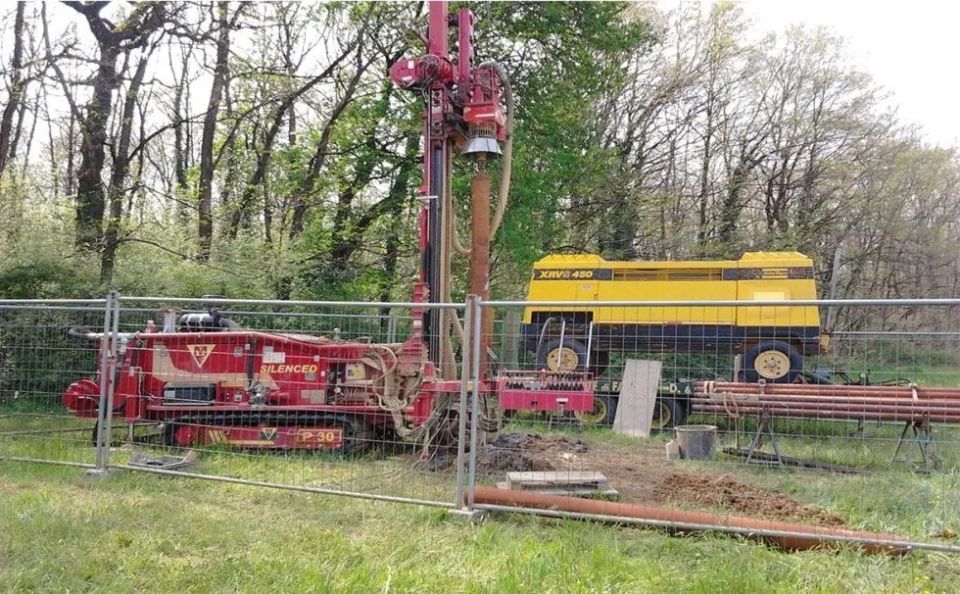 Piattaforma di perforazione in un cantiere edile. Macchina rossa, rimorchio giallo e tubi marroni.