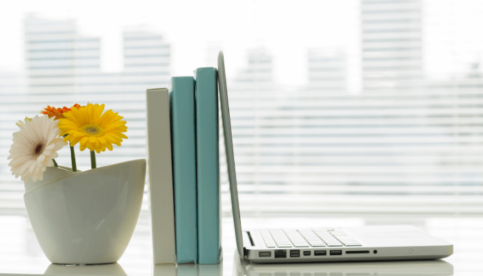 Laptop on organized desk with bouquet of flowers.