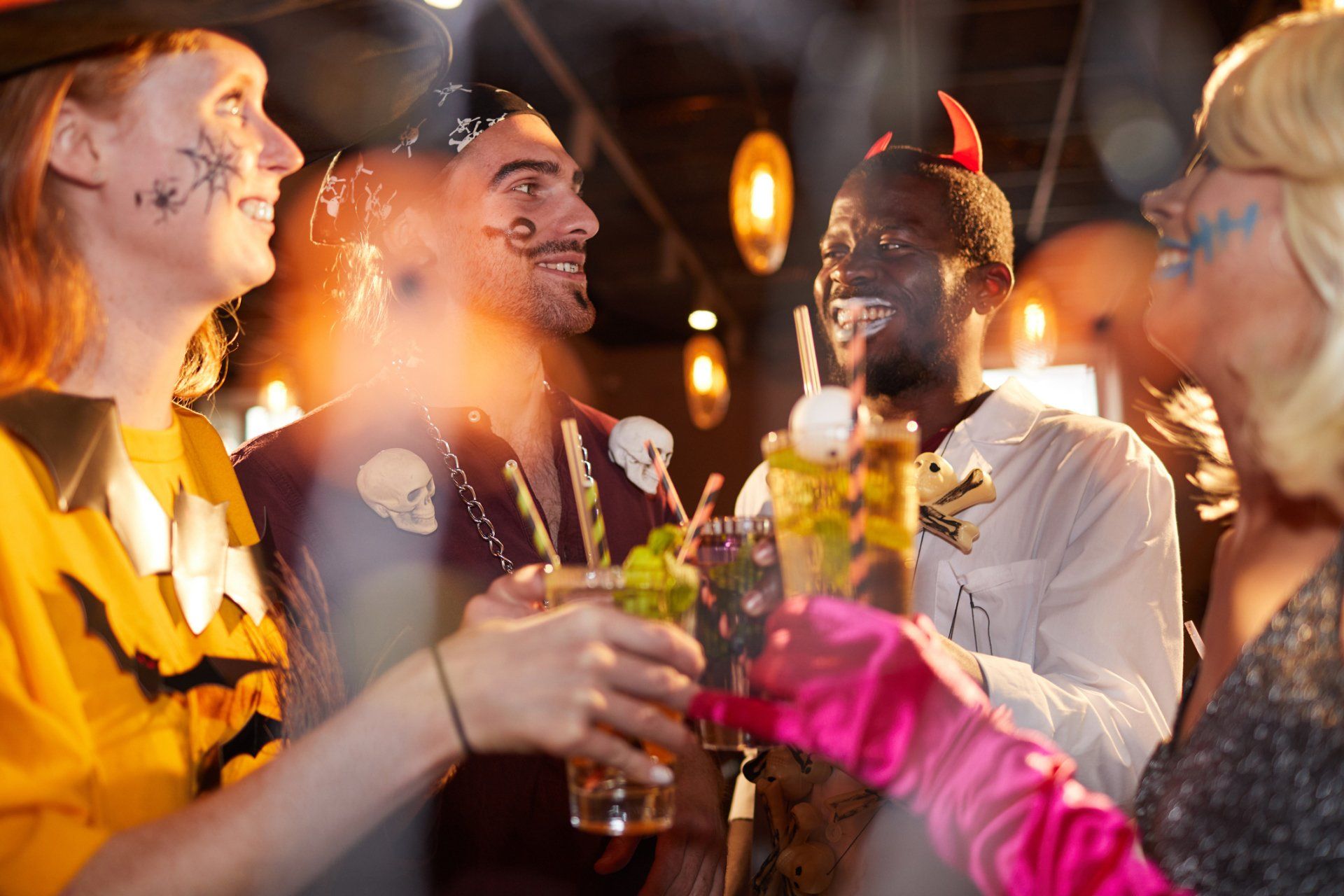 A group of people are toasting with drinks at a halloween party.