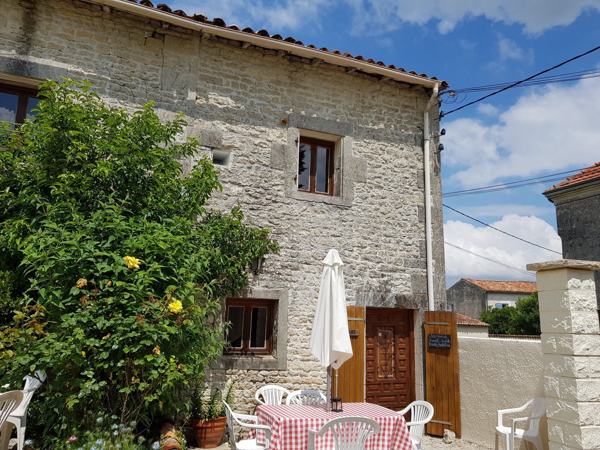 External view of Grenier holiday cottage with a red and white checked table cloth on the garden table