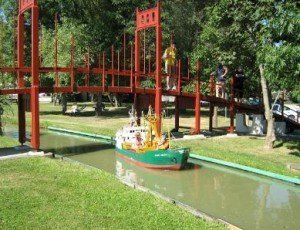 miniature boat sailing under a bridge