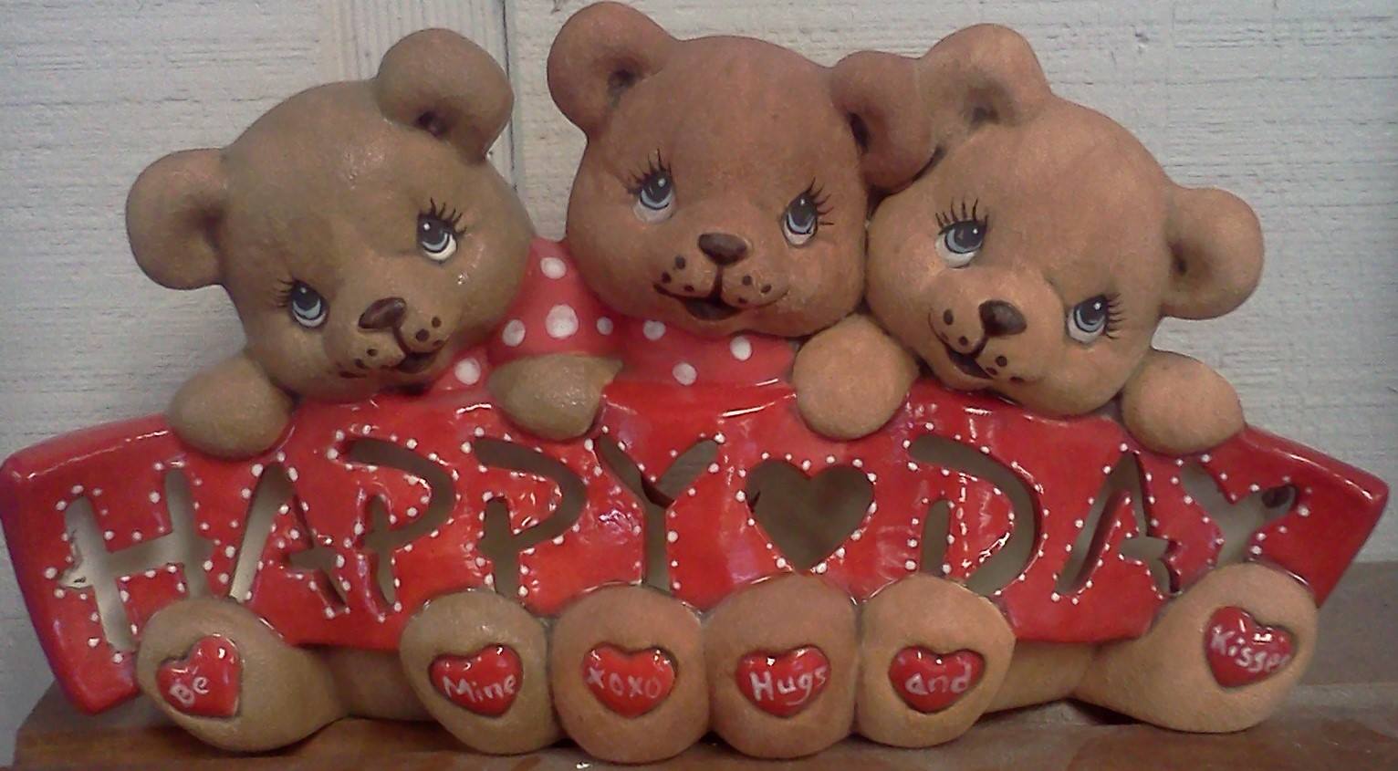 Three teddy bears sitting on top of a sign that says happy day