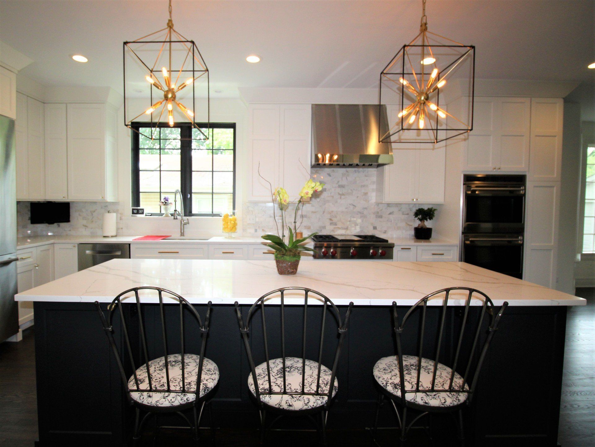 A kitchen with a large island and three chairs.