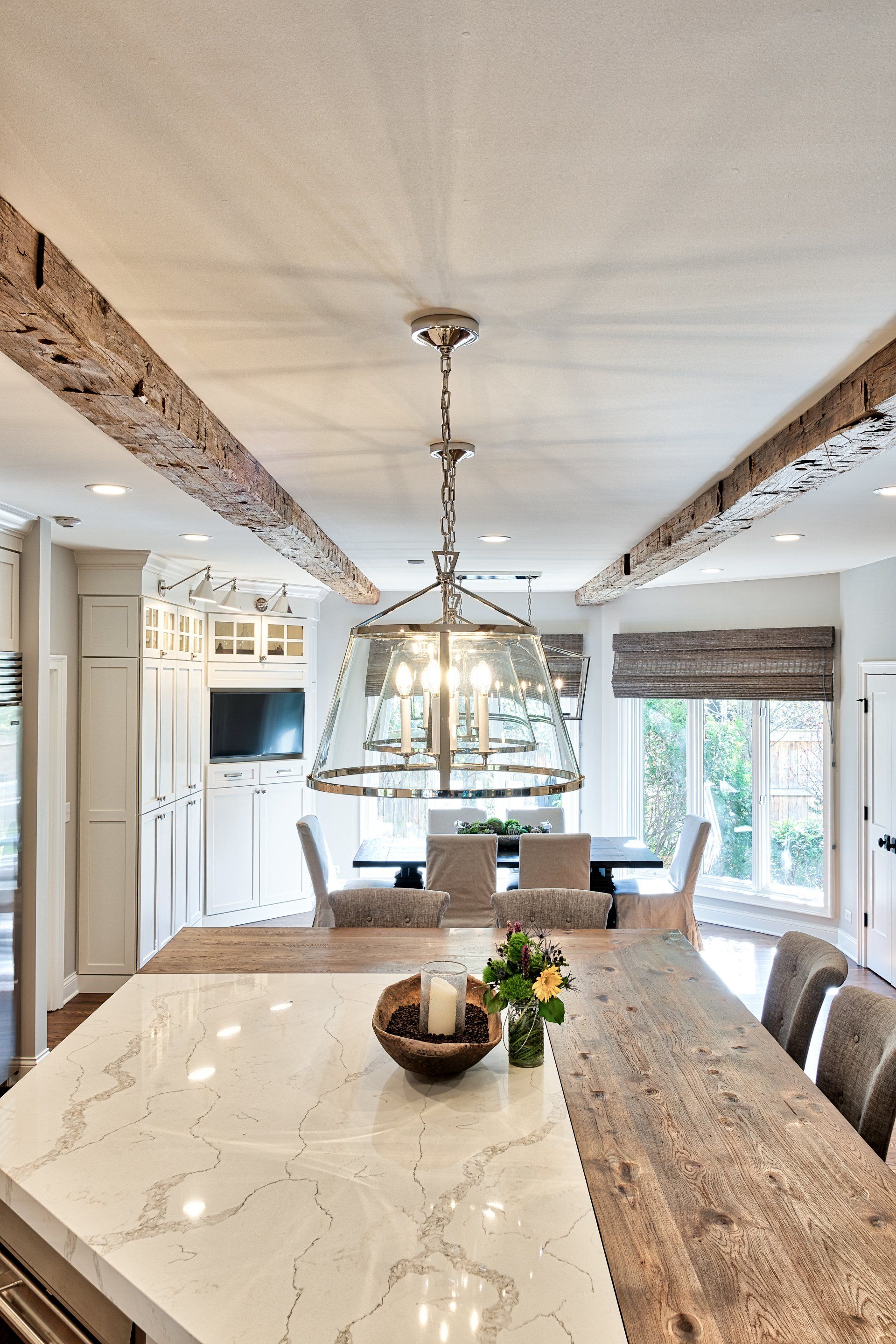 A kitchen with a large table and chairs and a chandelier hanging from the ceiling.