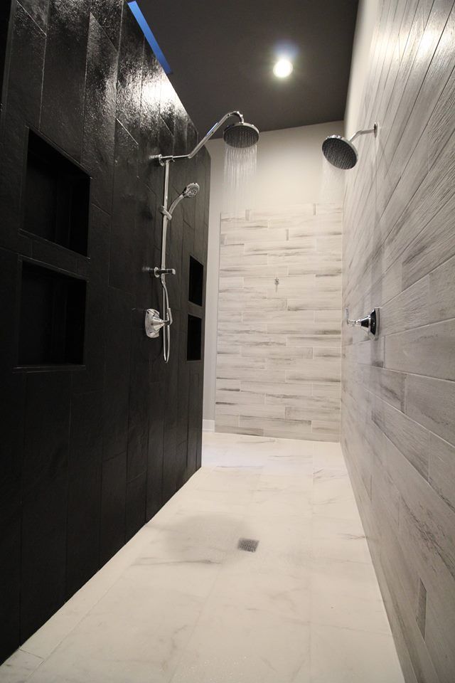 A bathroom with two showers and a black wall.