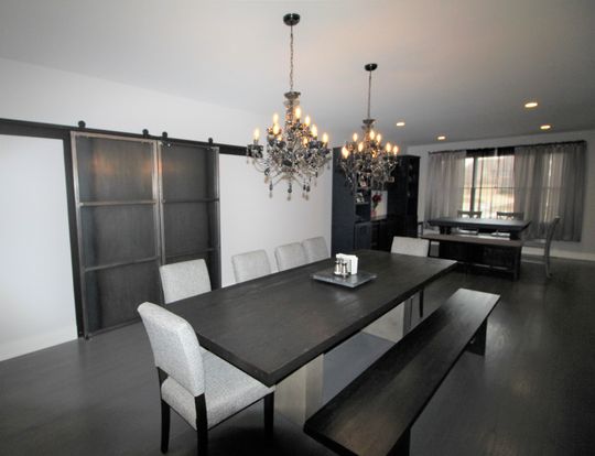 A dining room with a table and chairs and two chandeliers