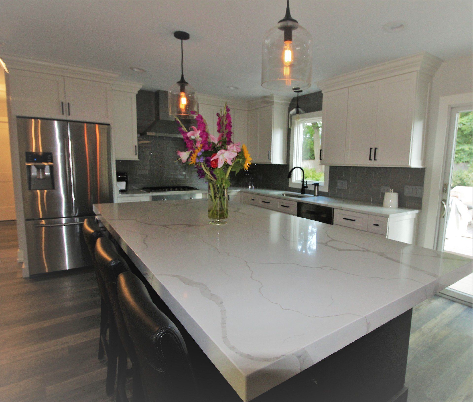 A kitchen with a large island and a vase of flowers on it.