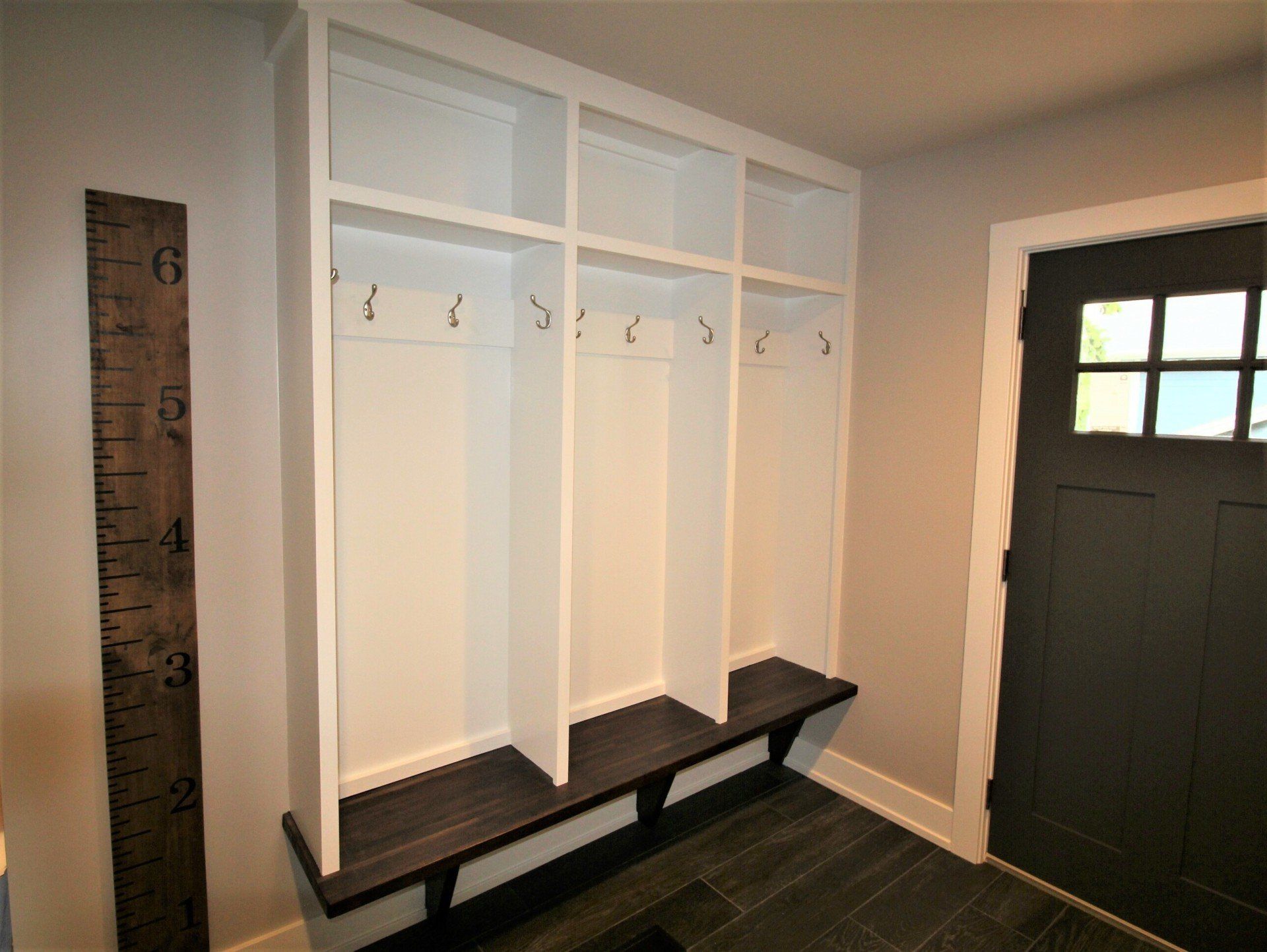 A mud room with a black door and a ruler on the wall.