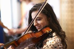 college student playing violin in recording studio