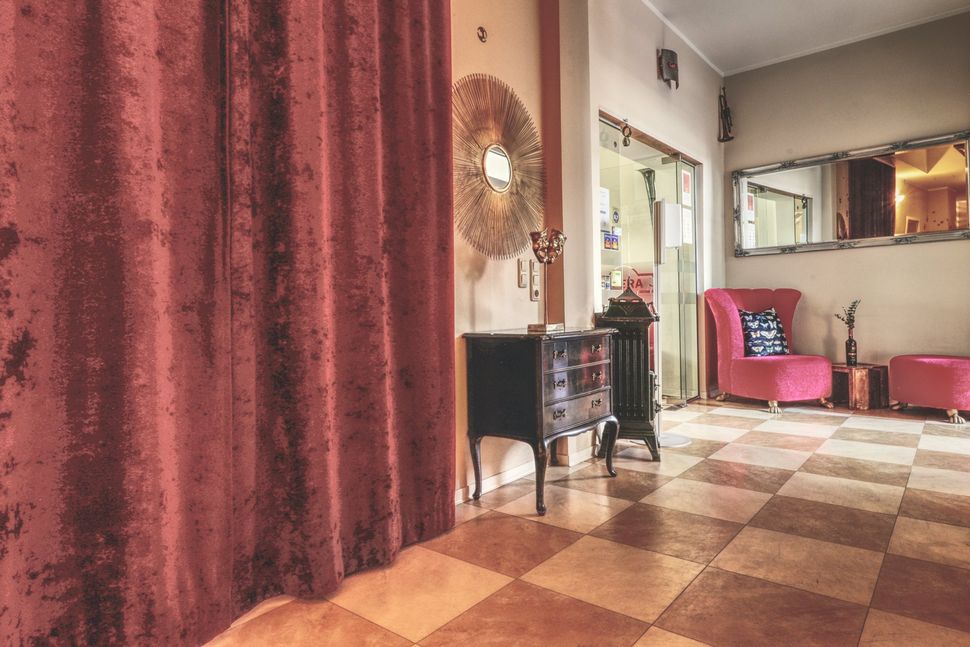 Willkommen im OPERA Hostel – Rezeption mit Lounge-Vibe und roten Vorhängen
