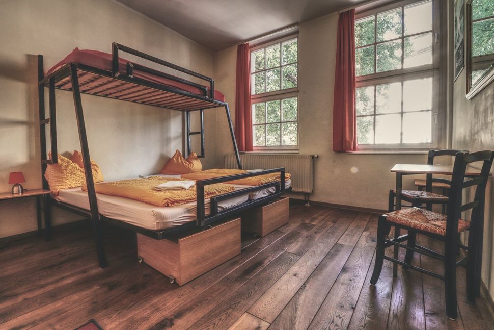 Gemütliches Hostelzimmer „Kurt“ mit Hochbett, Holzfußboden und Tisch