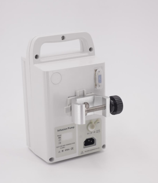 White infusion pump with handle and clamp, back view, on a white surface.