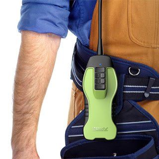 A person's arm and tool belt with a lime green device attached, likely for communication or data collection.