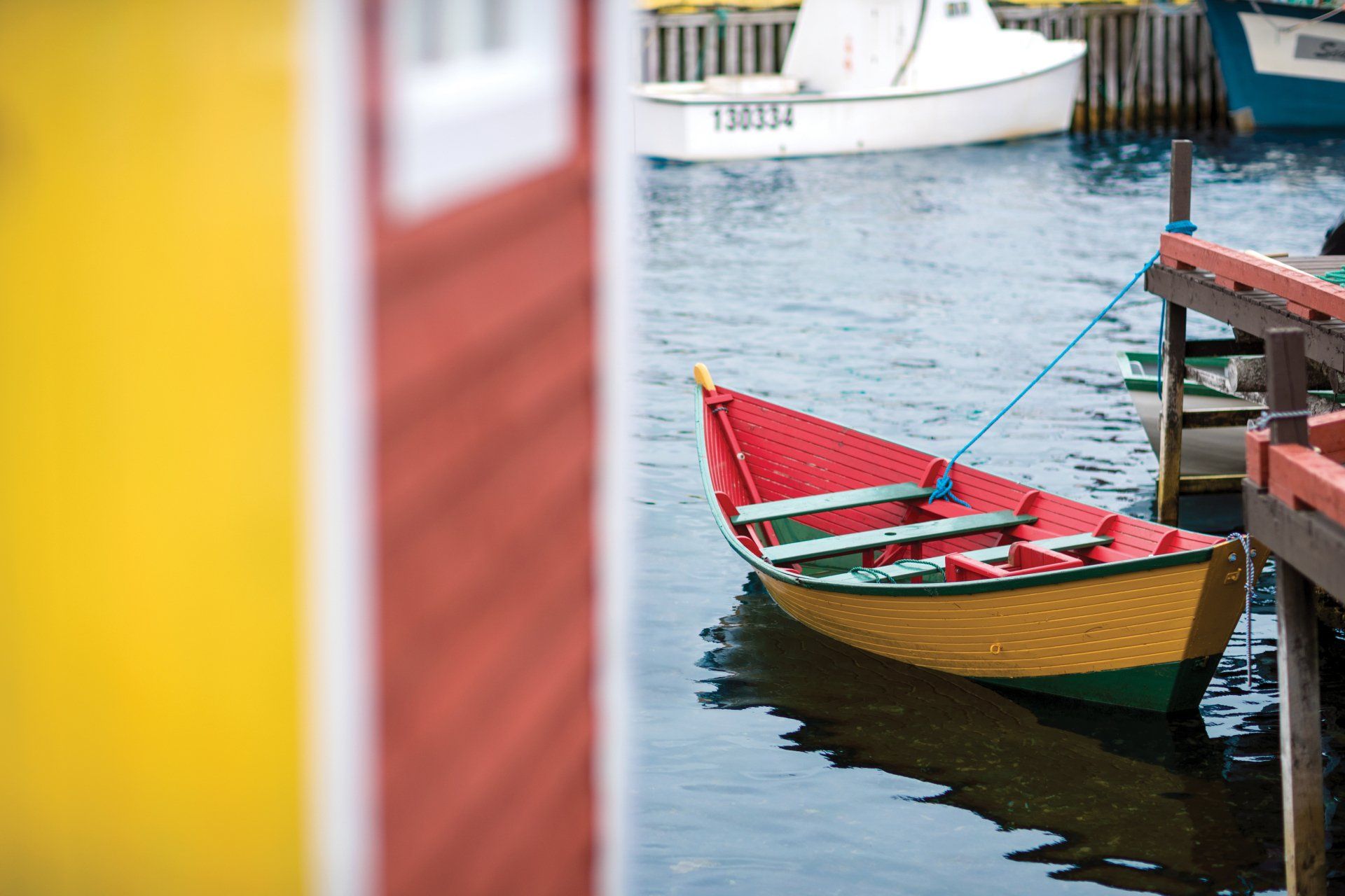 Un dory jaune, un bateau traditionnel terre-neuvien, amarré à un ponton près d'un cabanon