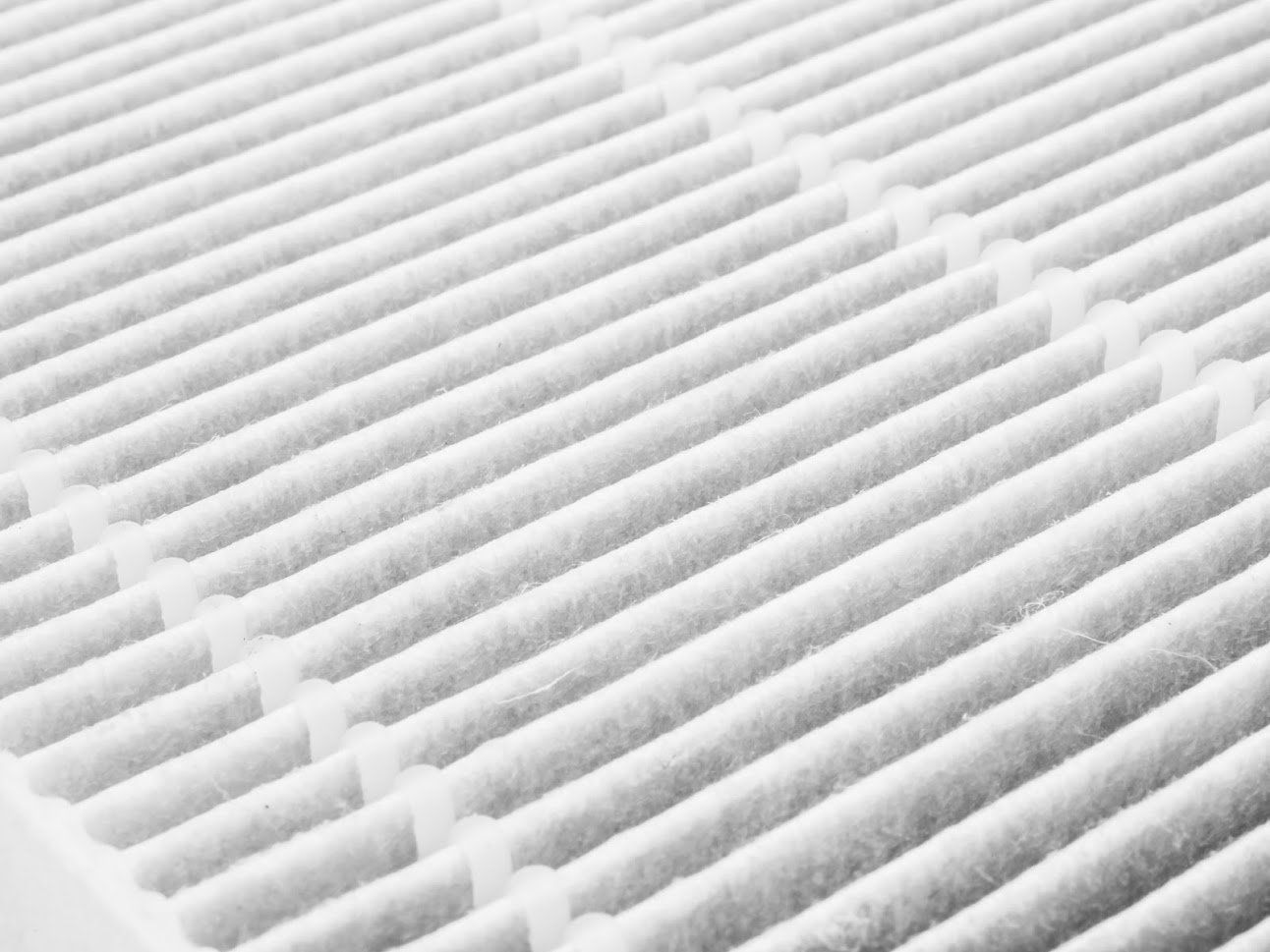 Close-up of a white air filter with a grid-like pattern, showing rows of folded filter material.