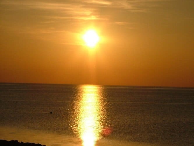 Golden sunset over the ocean; sunlight reflects on the water.