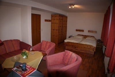 Cozy hotel room with a double bed, two armchairs, a sofa, and a table. Wooden furniture dominates the space.