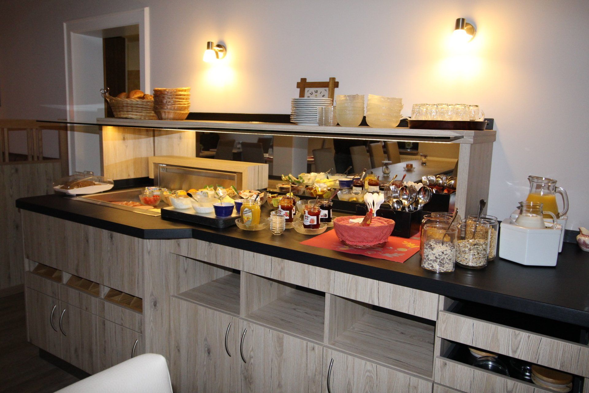 Buffet table with various breakfast foods, including bread, fruit, and jams, set in a dining area.