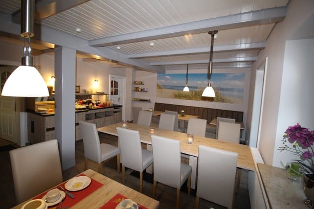 Bright dining room with a long table set for a meal. A mural of a beach scene is on the back wall.