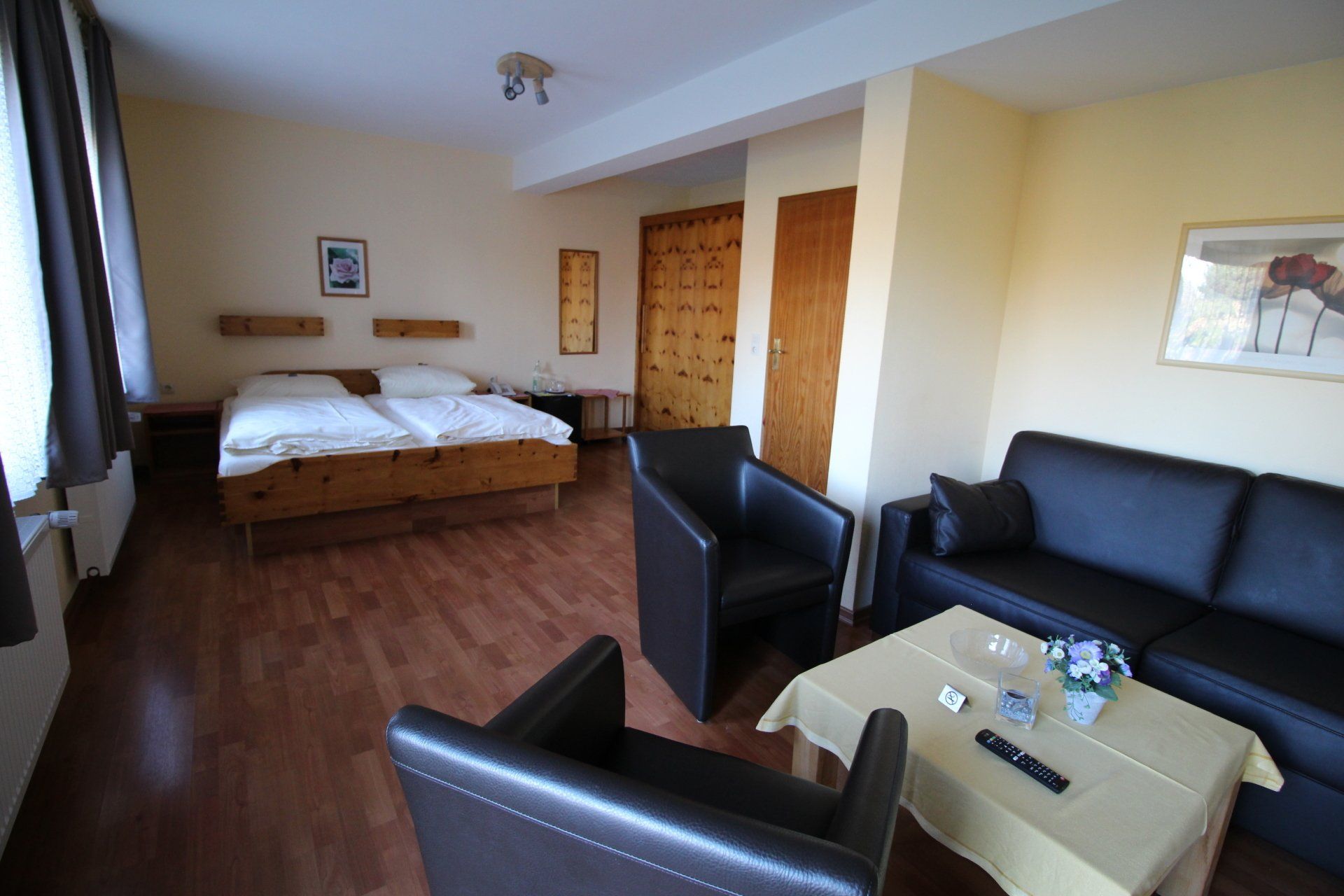 A hotel room with a bed, two leather armchairs, a black sofa, and a coffee table. 