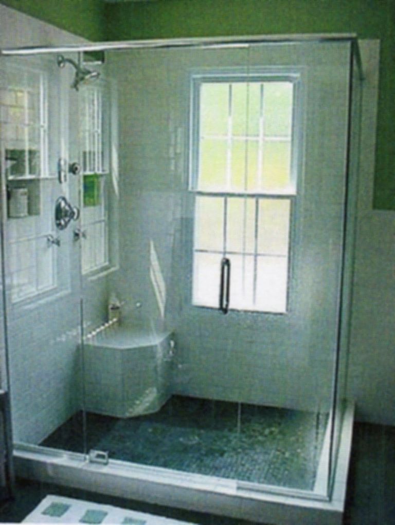 Glass shower with tiled walls and a window inside. Features a built-in seat and showerhead.