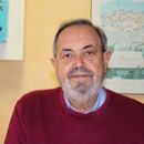 Un uomo con la barba indossa un maglione rosso e una camicia blu.
