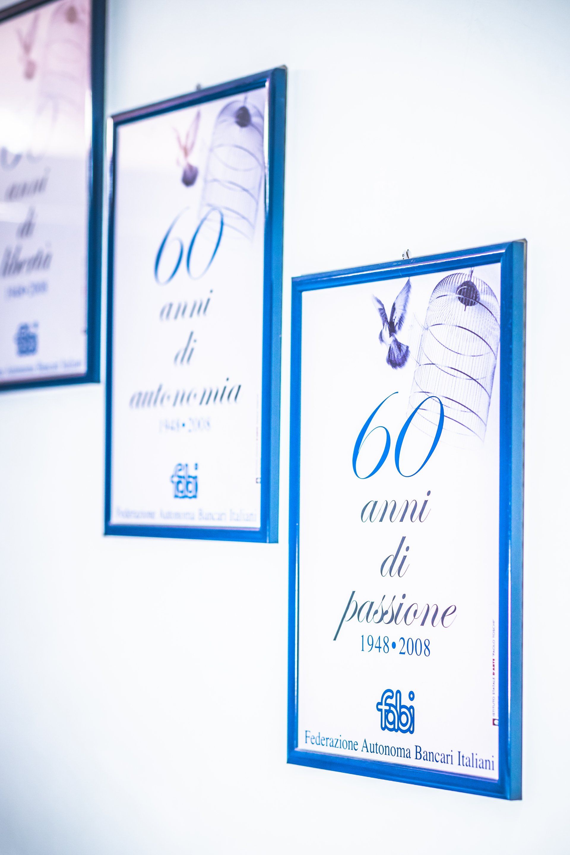 Tre poster incorniciati sono appesi su un muro bianco.