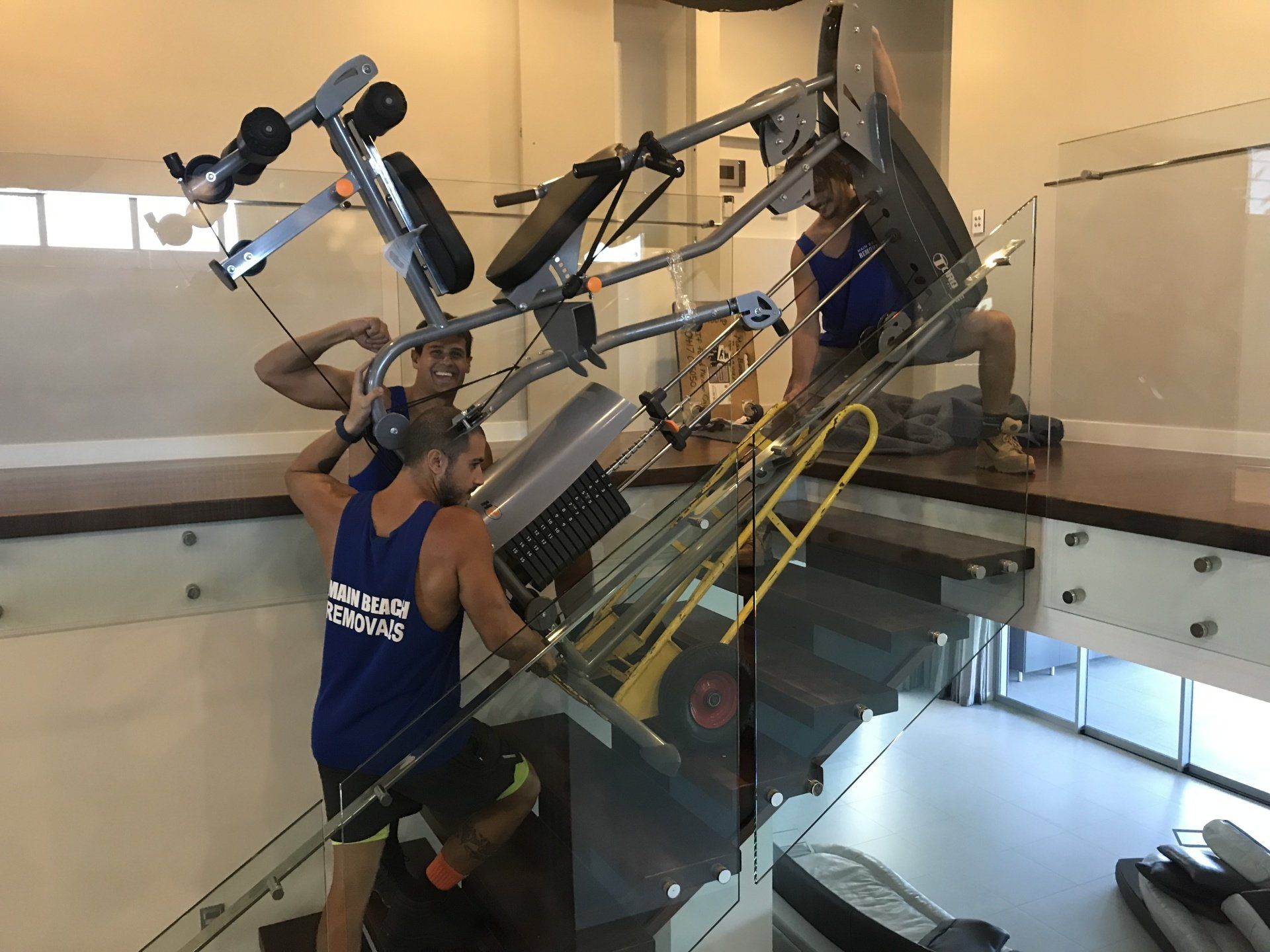 Two men are carrying a exercise machine up a set of stairs.