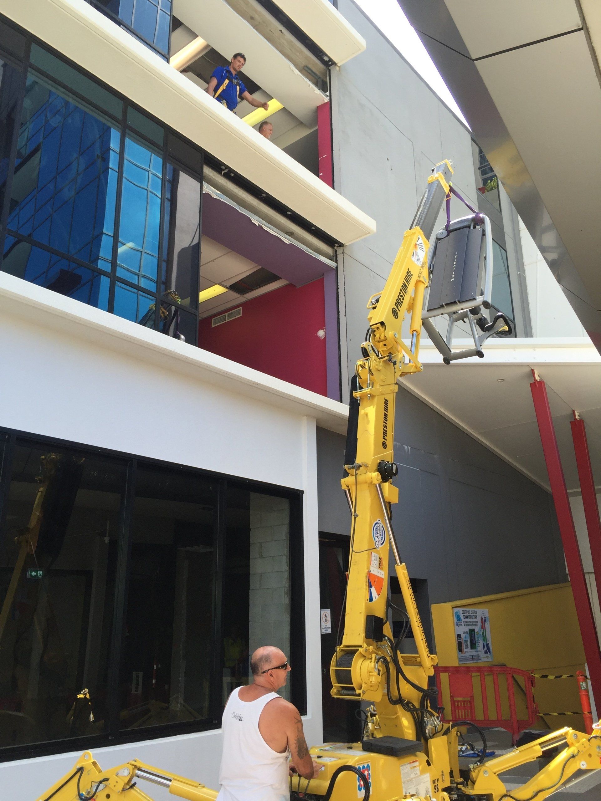 A man is working on a building with a yellow crane
