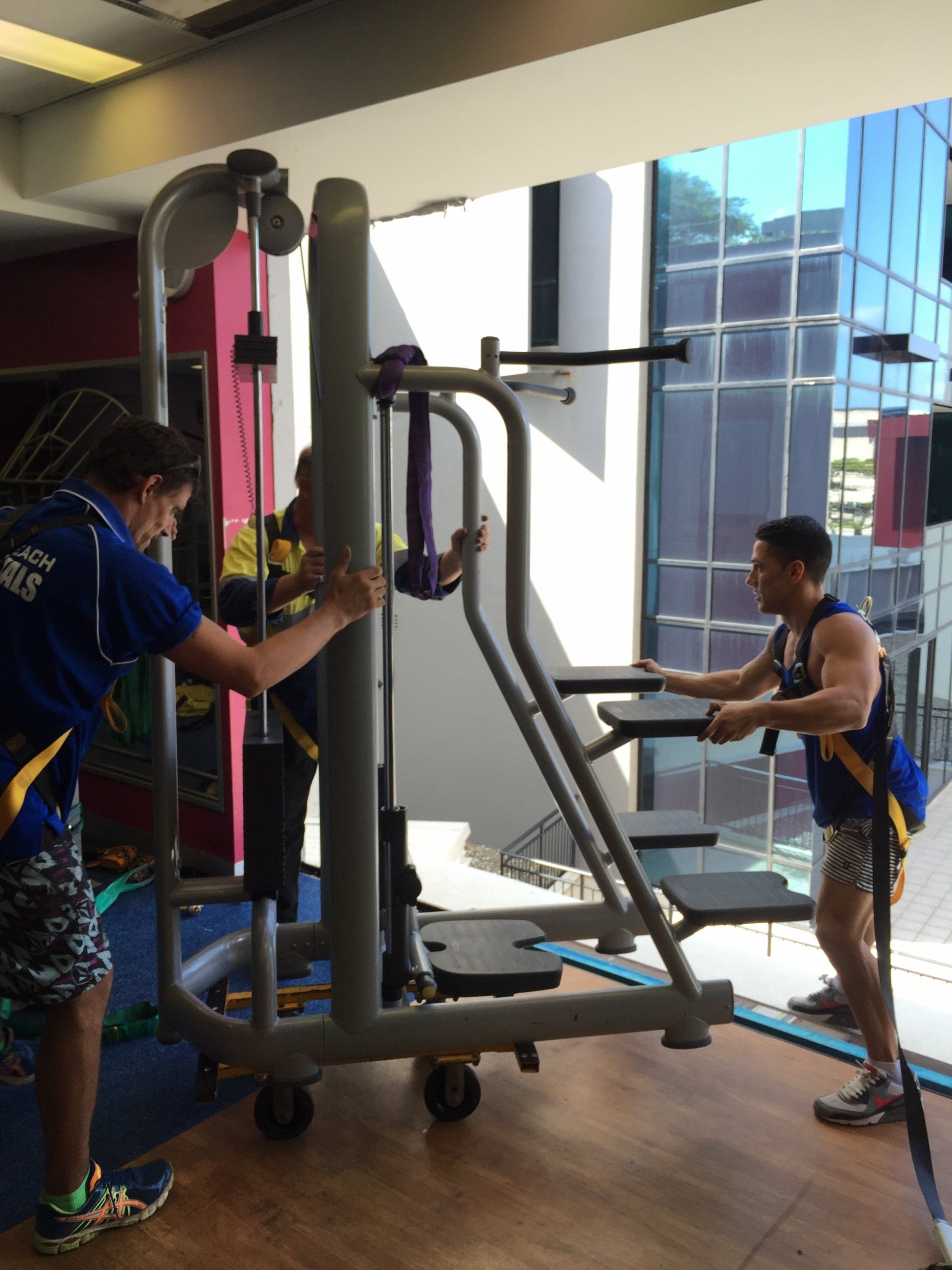 Two men are working out in a gym with one wearing a shirt that says ' rugby ' on it