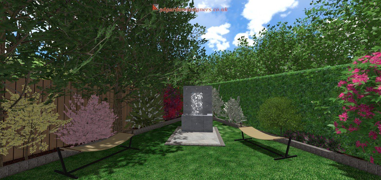 A backyard with a water fountain, lush greenery, grass, and lounge chair under a bright sky.