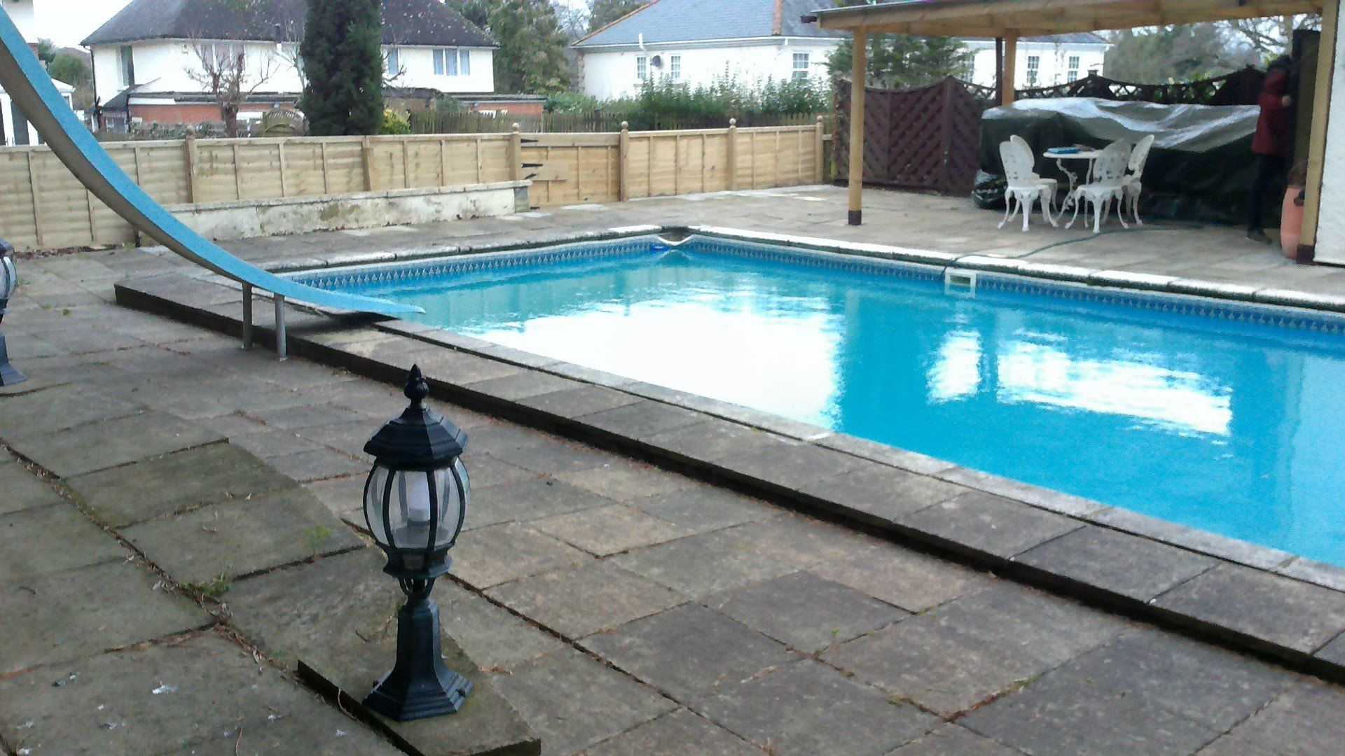 Backyard with rectangular swimming pool, slide, patio, and partially covered seating area.
