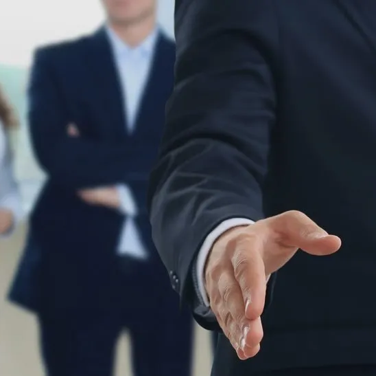 A man in a suit is reaching out to shake someone 's hand