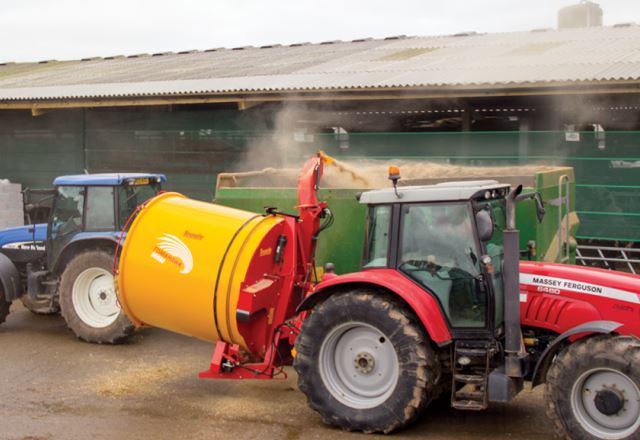 Rød traktor, der trækker en gul gyllevogn på en gårdsplads, med en blå traktor parkeret bagved.