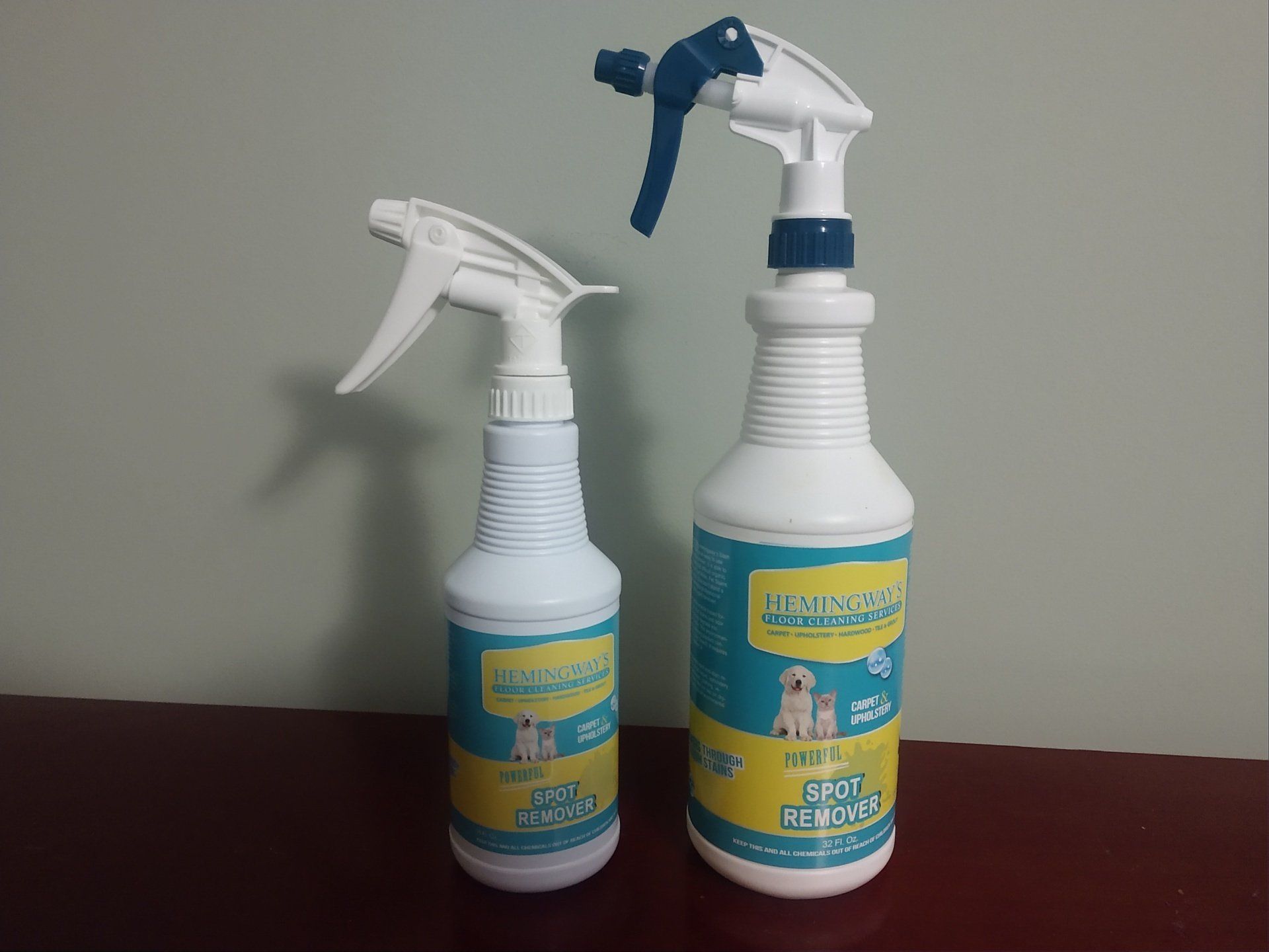 Two white spray bottles with blue and white spray nozzles on a table.