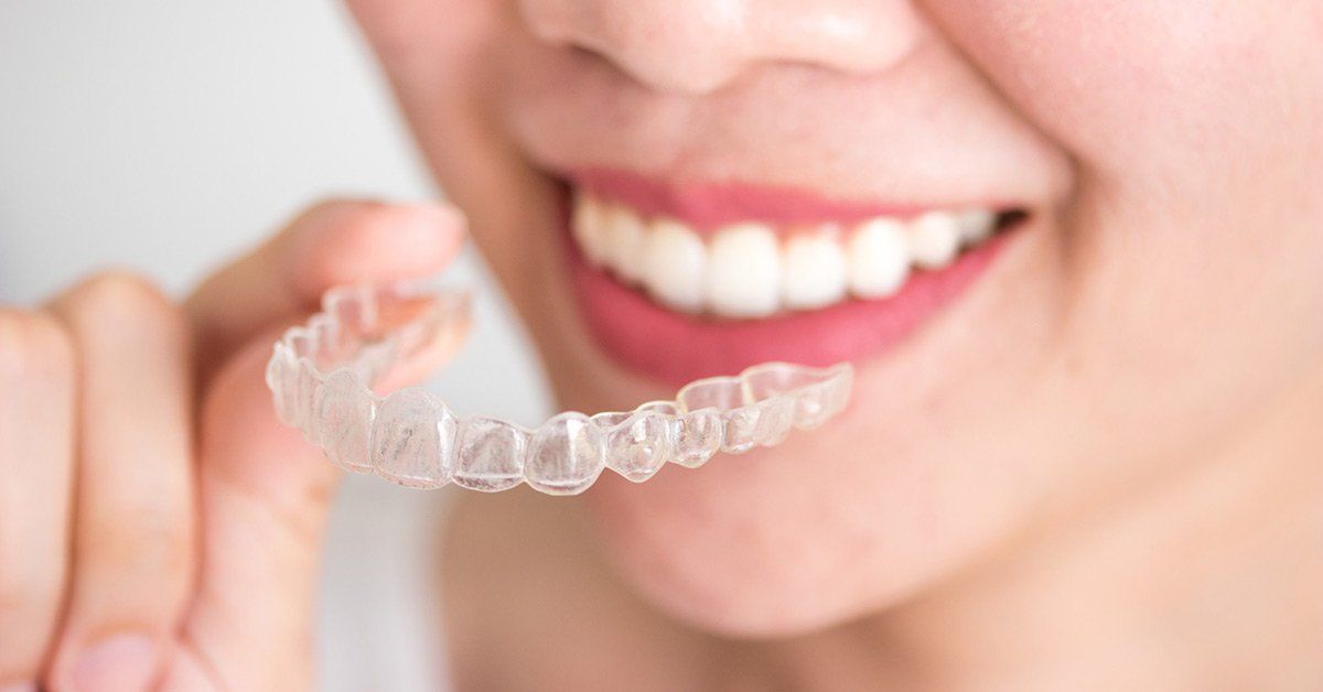 A woman is holding a clear brace in her mouth.