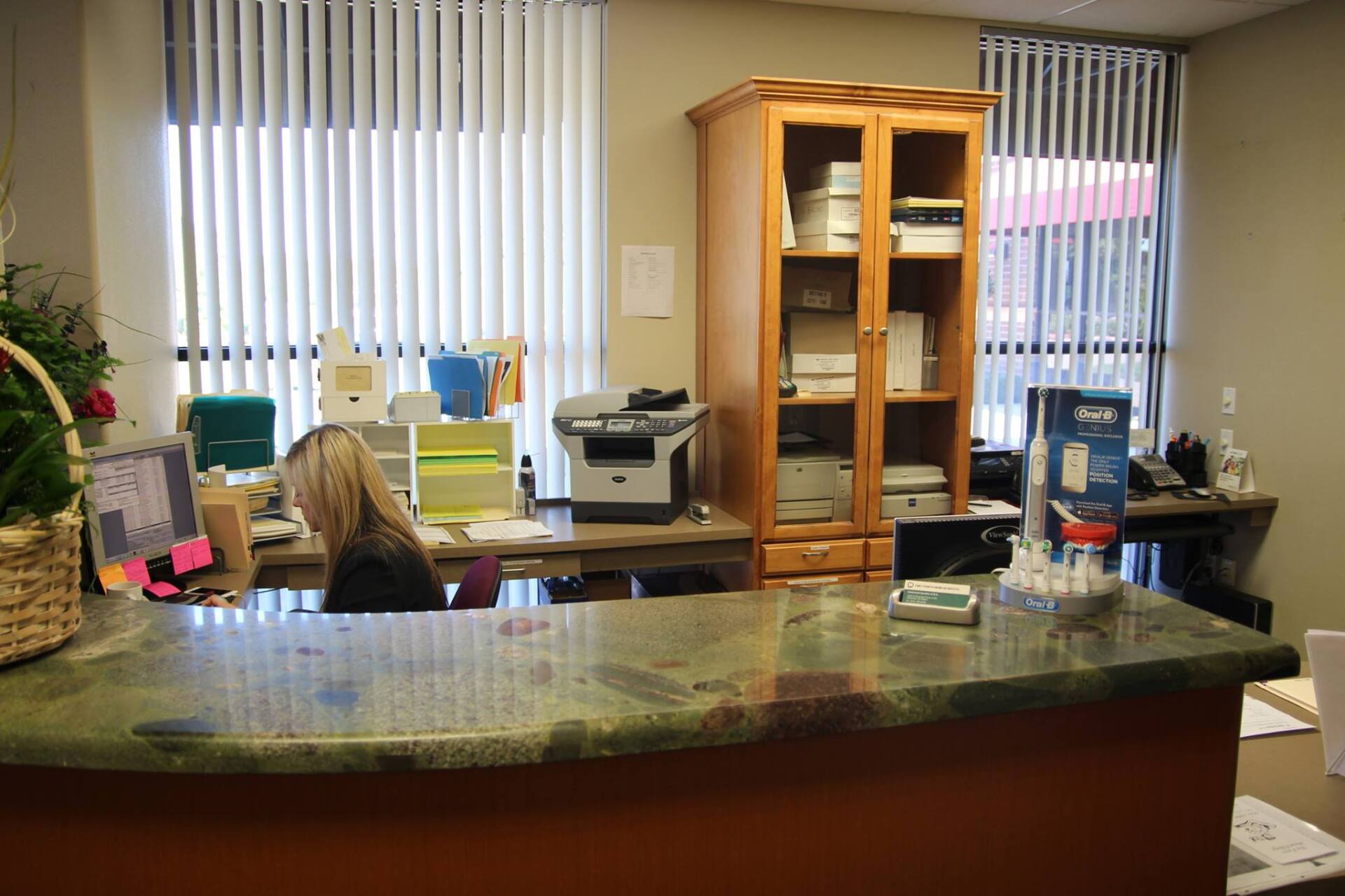 A woman is sitting at a desk in a reception area.