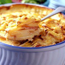 Close-up van een aardappelgratin in een blauwgerande schaal, bedekt met gesmolten kaas en een lepel.