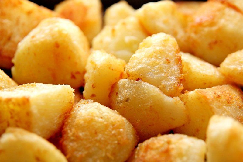 Goudbruin geroosterde aardappelblokjes met een knapperig, gekruid laagje, dicht op elkaar gestapeld.