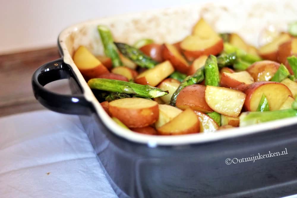 Geroosterde groenten met asperges en aardappelen in een zwarte ovenschaal