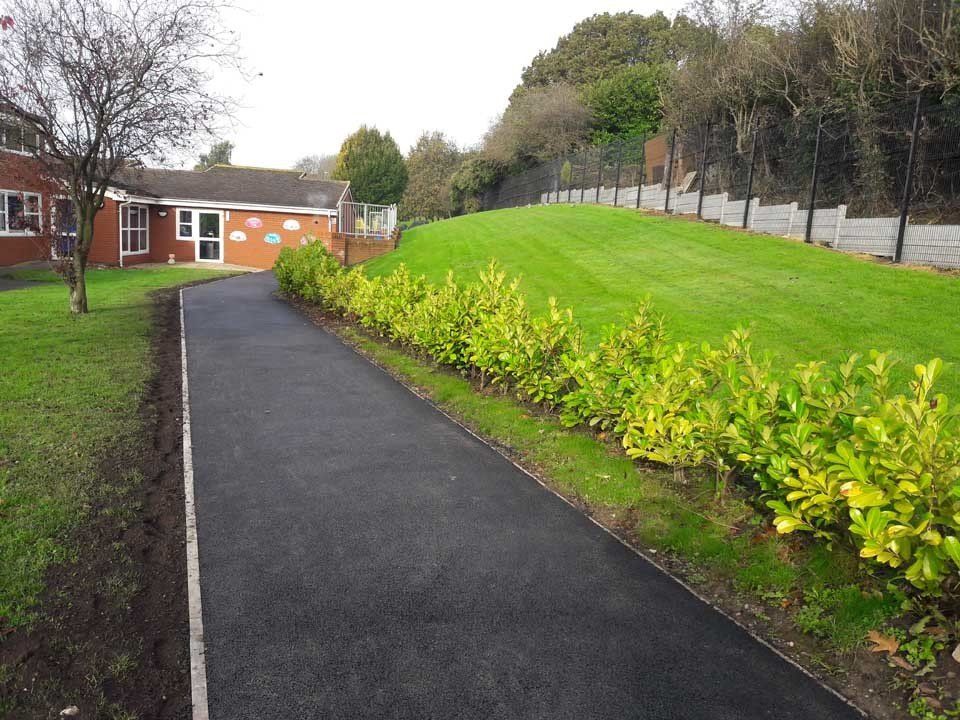 A path leading to a house with a grassy hill in the background