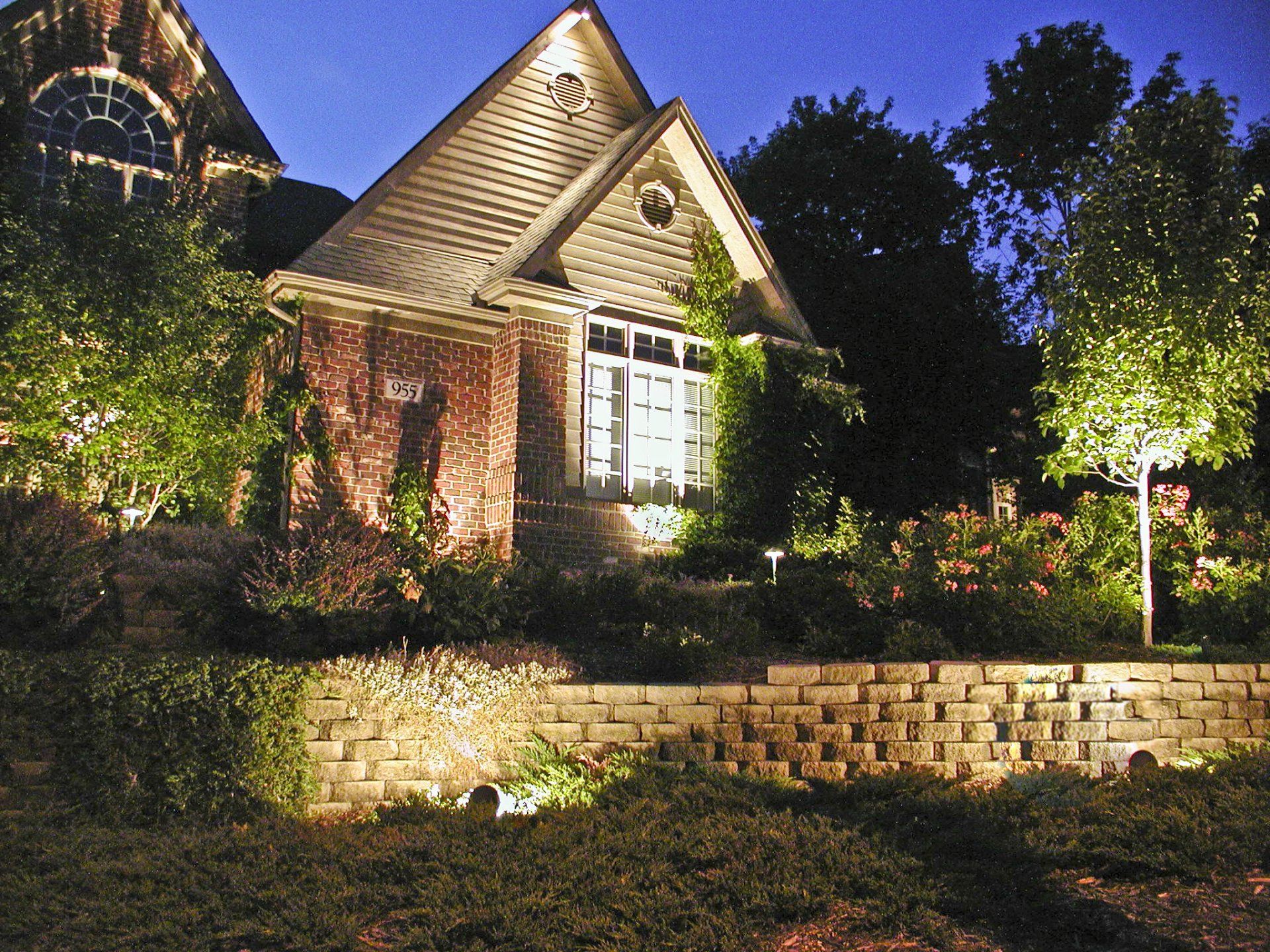 A house is lit up at night with a brick wall in front of it