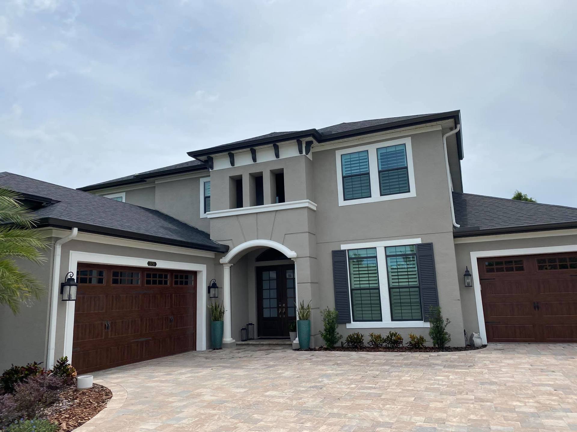 Modern two-story house with stucco exterior, double garage doors, and a large paved driveway